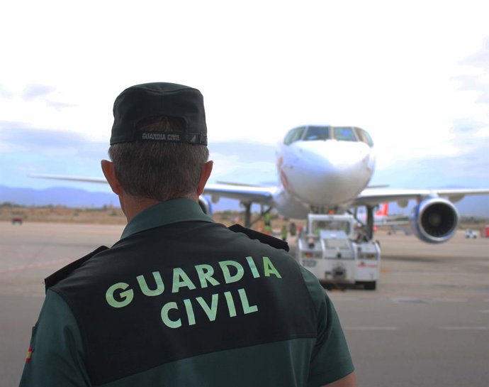 Archivo - Un agent de la Gurdia Civil, d'esquena, a la pista d'un aeroport amb un avió al fons