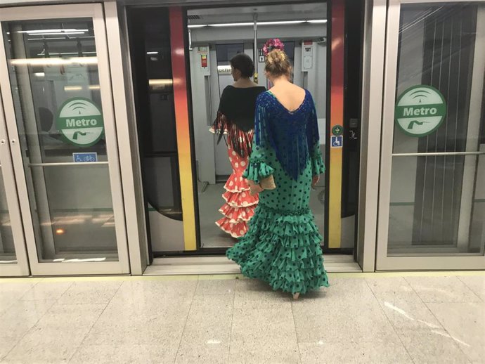 Dos mujeres vestidas de flamenca acceden a un vagón del Metro con destino a la Feria.