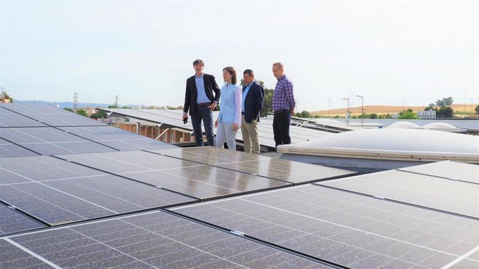 Casanueva (centro) observa las placas solares instaladas en la cubierta del un edificio del barrio del Guadalquivir.