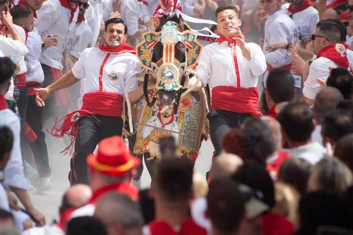 Varios jóvenes corren junto a su caballo en la carrera de los Caballos del Vino de Caravaca de la Cruz (Murcia)