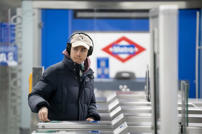 Archivo - Joven pasando el título de transportes por un torno de Metro de Madrid