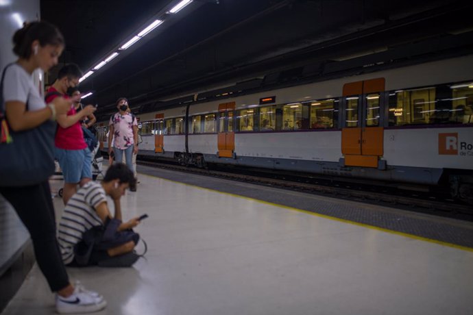Archivo - Viajeros esperan la llegada de un tren de Rodalies