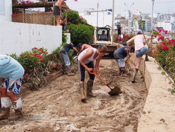 Archivo - Personas retiran lodo tras las lluvias provocadas por el paso del ciclón Yaku por Perú