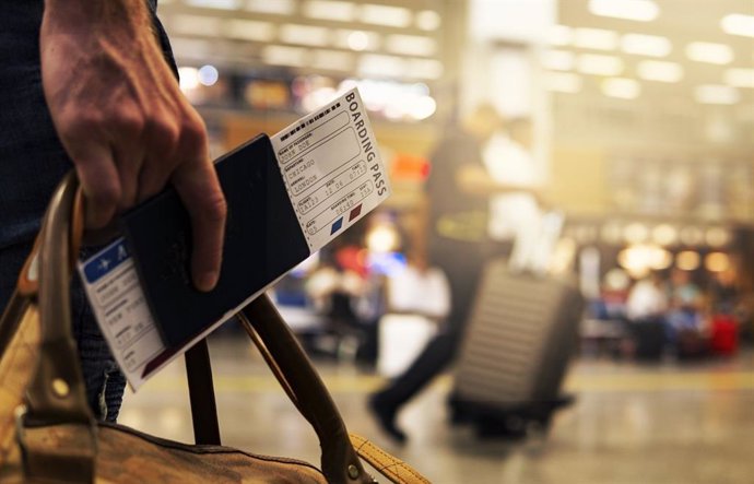 Persona en un aeropuerto con el billete y el pasaporte en la mano
