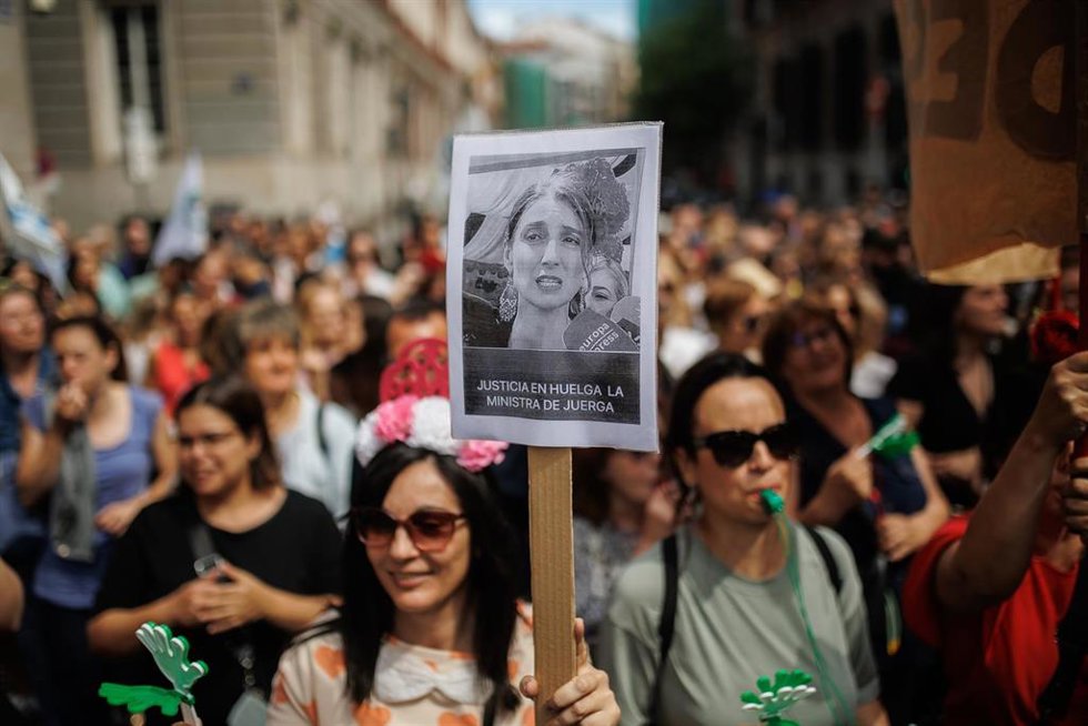 Manifestante con una pancarta que reza: 'Justicia en huelga, la ministra de juerga' durante una concentración de funcionarios de la administración de Justicia, frente al Ministerio.