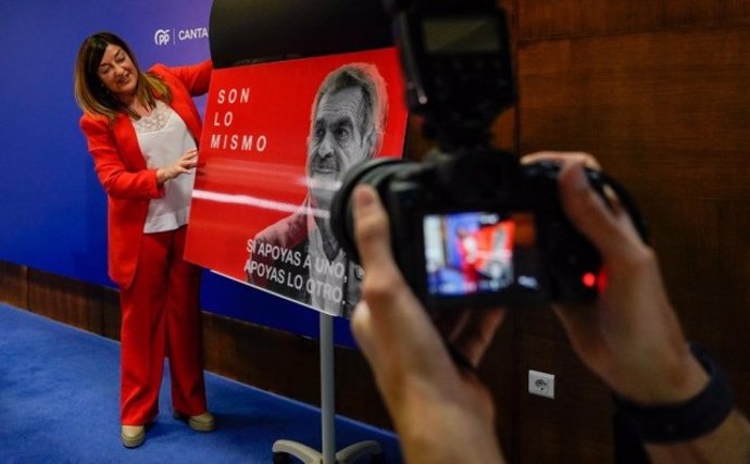 La presidenta del PP de Cantabria, María José Sáenz de Buruaga, mostrando el cartel con las caras de Revilla y Sánchez