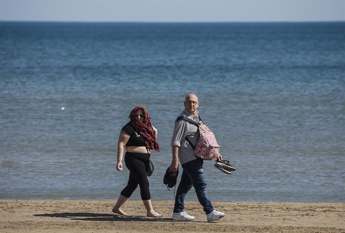 Archivo - Varias personas pasean por la orilla de la playa de La Malvarrosa