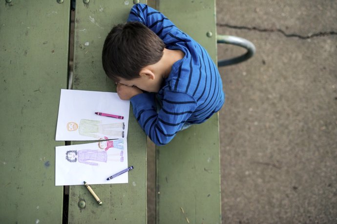 Archivo - Foto de un niño triste junto a un dibujo