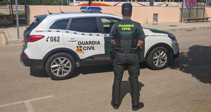 Un agente de la Guardia Civil, de espaldas, junto a un vehículo.