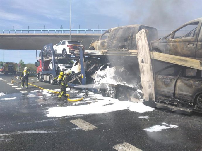 Bomberos apagando el incendio en el camión portacoches