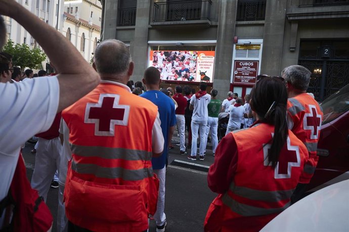 Archivo - Trabajadores de Cruz Roja observan por una pantalla un encierro de los Sanfermines de 2022.