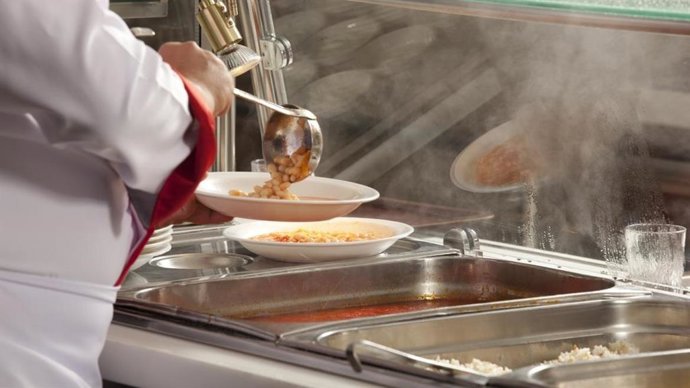Archivo - Una persona sirve comida en una bandeja en un comedor escolar.