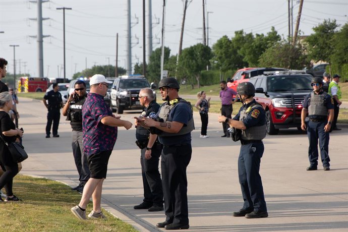 HOUSTON, May 7, 2023  -- A police officer talks with a witness near the shooting site of Allen Premium Outlets in Allen, a suburban city of Dallas, Texas, the United States, May 6, 2023. Nine people were killed, including the shooter, and seven others w