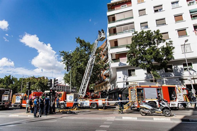 Dos bomberos subidos en una grúa en el edificio donde ha ocurrido un incendio, en la Glorieta de Embajadores, a 9 de mayo de 2023, en Madrid (España). 