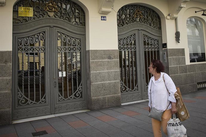 Archivo - Una mujer observa el anuncio de un piso en venta en Madrid.