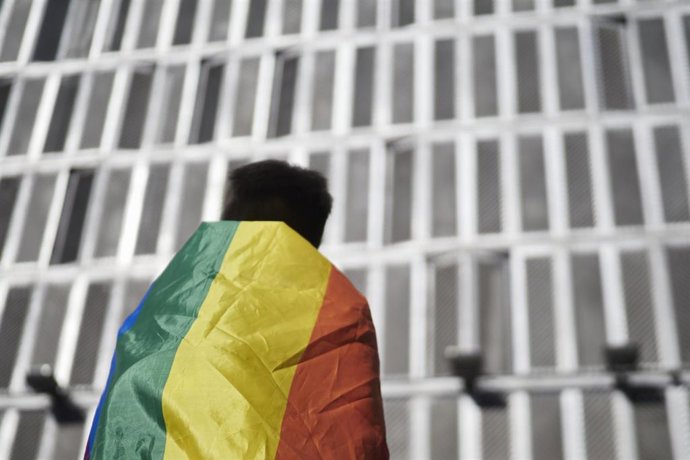 Archivo - Una persona viste con una bandera durante una manifestación por el Orgullo LGTBI.