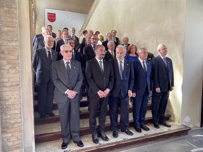 El presidente del Gobierno de Aragón, Javier Lambán, y el presidente de las Cortes, Javier Sada, junto con los miembros de la RAE en las esclares de acceso al Salón del Trono de La Aljafería.