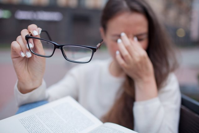 Archivo - Closeup portrait of attractive female with eyeglasses in hand. Poor young girl has issues with vision. She rubs her nose and eyes out of fatigue. A student tired to study and read books