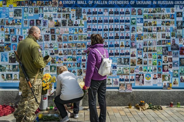 May 9, 2023, Kyiv, Kyiv, Ukraine: A soldier and a couple lay flowers in the Memory Wall of fallen defenders of Ukraine in the current Russia invasion of Ukraine during the funeral of Danylo Denysevych, a killed soldier in Bakhmut combats.