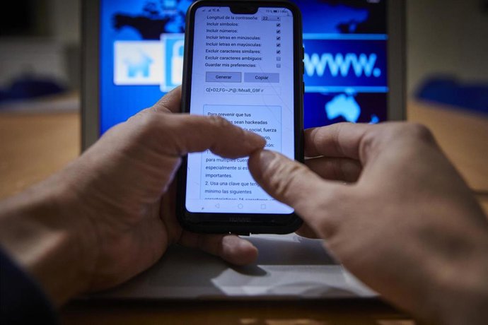 Archivo - Una persona con el móvil y el ordenador encendidos, en Madrid (España), a 9 de febrero de 2021.  Este martes 9 de febrero se celebra el Día de la Internet Segura, que en esta edición está inevitablemente marcado por la pandemia y el confinamie