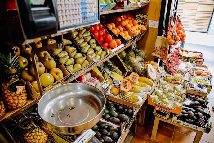 Archivo - Una balanza y varias piezas de frutas y hortalizas en una frutería