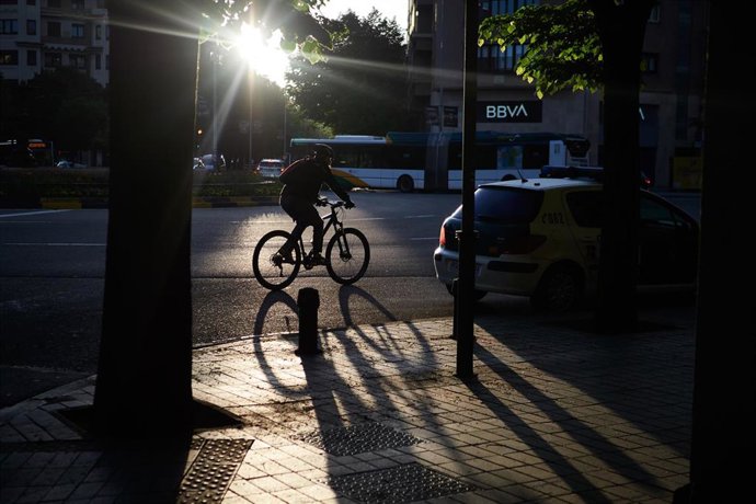Archivo - Una persona circula con una bicicleta por una glorieta.