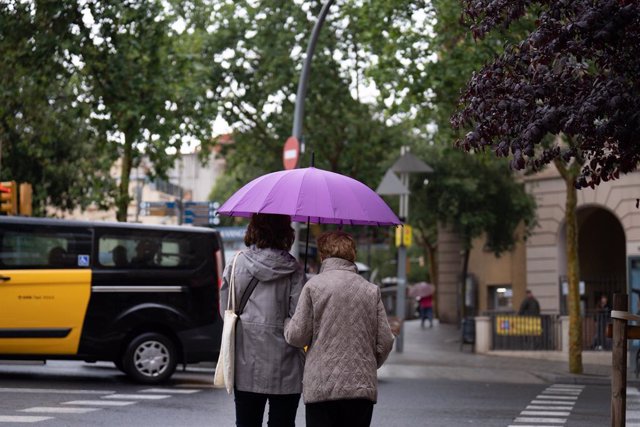 Diverses persones amb paraigües passegen per un dels carrers de la ciutat de Barcelona