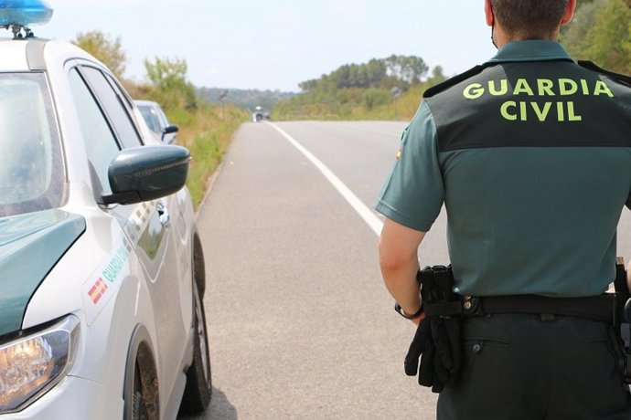 Archivo - Un agente de la Guardia Civil junto a un coche, archivo 