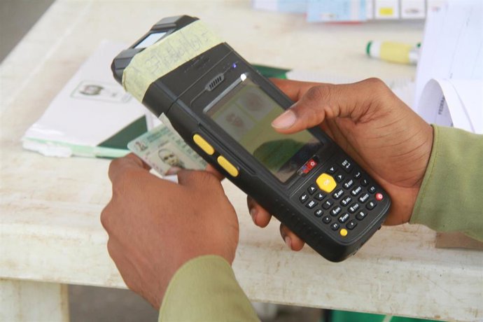 Archivo - Una persona revisa una identificación de una persona que vota en las elecciones en Nigeria