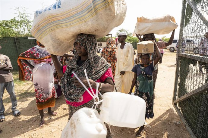 Archivo - Desplazados internos sudaneses llevan artículos humanitarios suministrados por agencias internacionales como ACNUR