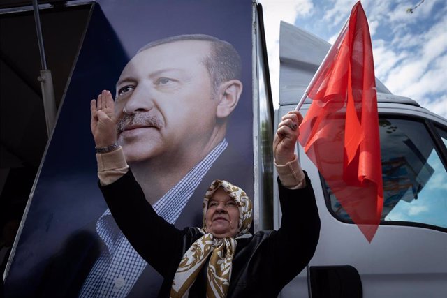 Una mujer con una bandera turca delante de un retrato del presidente del país, Recep Tayyip Erdogan