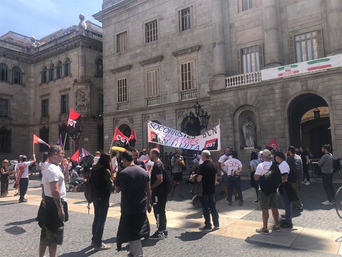 Unos 30 socorristas se concentran ante el Ayuntamiento de Barcelona el primer día de huelga indefinida.