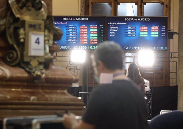 Archivo - Un hombre delante de dos paneles con valores del Ibex 35, en el Palacio de la Bolsa, a 4 de febrero de 2022, en Madrid (España). El Ibex 35 ha retrocedido un 1,19% en la media sesión de este viernes, lo que le llevaba a perder la cota de los 8.6