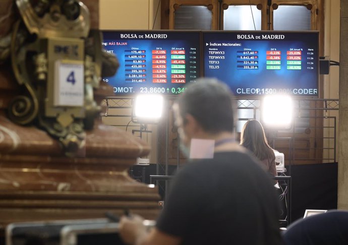 Archivo - Un hombre delante de dos paneles con valores del Ibex 35, en el Palacio de la Bolsa, a 4 de febrero de 2022, en Madrid (España). El Ibex 35 ha retrocedido un 1,19% en la media sesión de este viernes, lo que le llevaba a perder la cota de los 8
