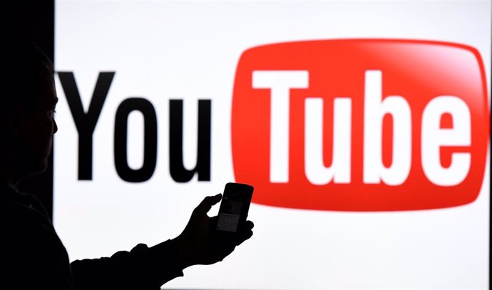 Archivo - FILED - 15 March 2019, Schleswig-Holstein, Aukrug-Homfeld: A man holds a smartphone in front of the logo of YouTube. 