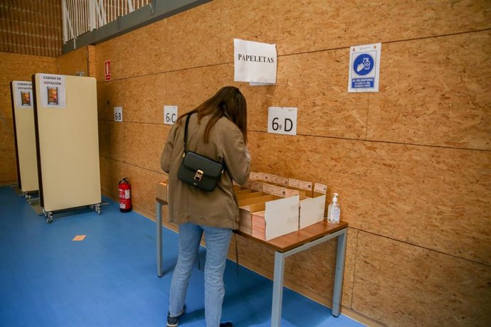 Archivo - Una mujer elige su papeleta electoral para ejercer su derecho a voto en el colegio San Agustín, a 4 de mayo de 2021, en Madrid (España)