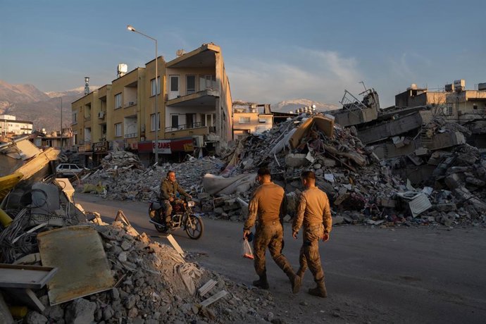 Archivo - Varias personas caminan por los escombros de los edificios derribados por el terremotoen Iskenderun, Turquía.