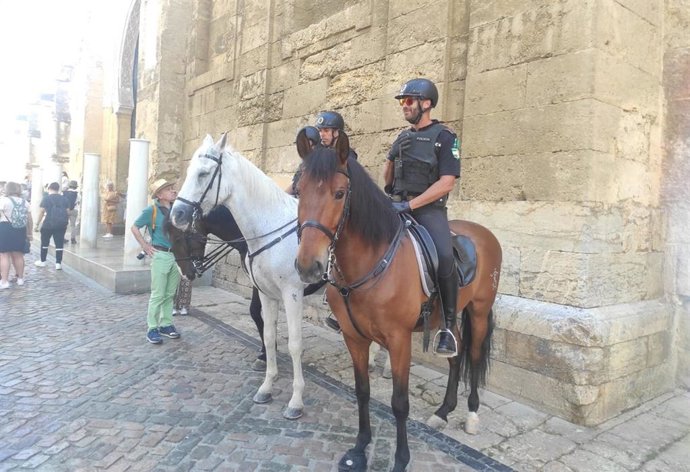 Policías locales a caballo atienden a turistas junto a la Mezquita-Catedral de Córdoba.