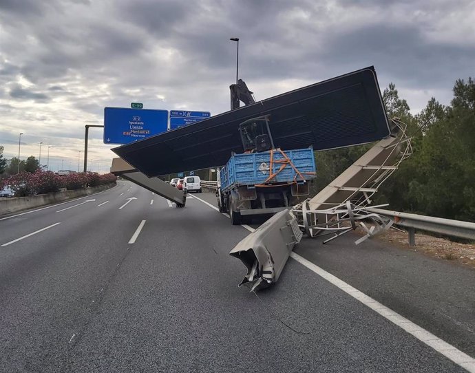 Un camión con la grúa pluma levantada tumba un pórtico de tráfico al chocar contra él en la autovía A-2 en Martorell (Barcelona).