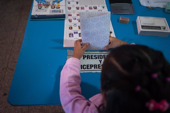 Archivo - June 16, 2019 - Quetzaltenango, Quetzaltenango, Guatemala - A child helps cast her mother's votes at a polling station during the first round of presidential election in Quetzaltenango in Guatemala June 16, 2019.