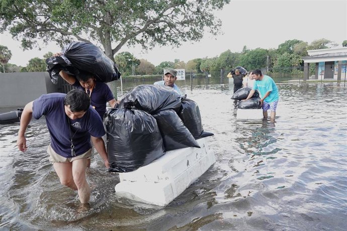 Archivo - 13 April 2023, US, Fort Lauderdale: People try and save valuables, wading through flood waters in the Edgewood neighbourhood of Fort Lauderdale, Florida. South Florida was drenched by rain Wednesday, causing major flooding. Photo: Joe Cavarett