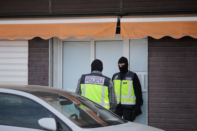 Dos agentes de la Policía Nacional en la puerta de un domicilio en Melilla por la opreación ante el posible fraude electoral por la compra de votos por correo