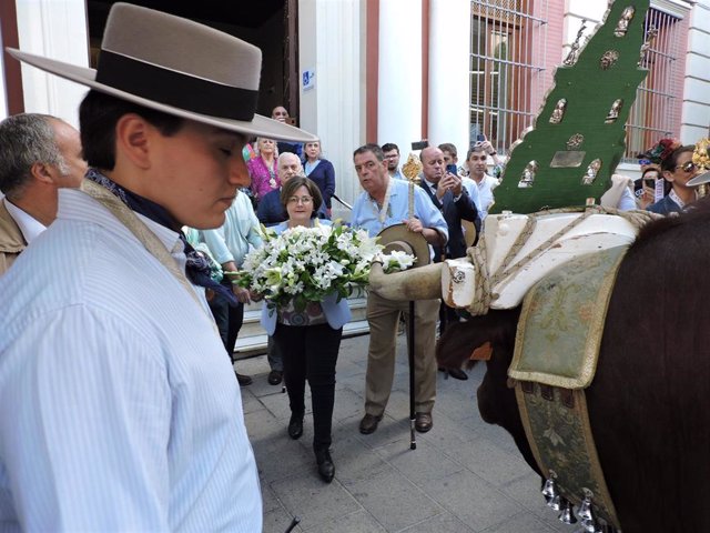 La diputada provincial de Cohesión Territorial, Asunción Llamas, deposita un ramo de flores en la carreta de la Hermandad del Rocío de Sevilla-El Salvador.