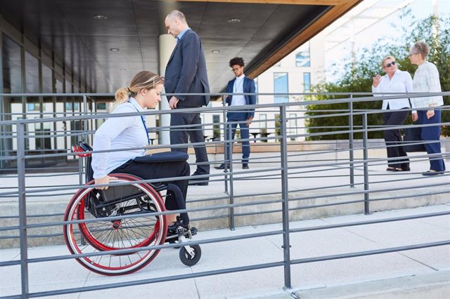 Archivo - Una persona en silla de ruedas accede por una rampa de un edificio público.