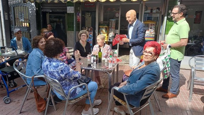 Hurtado reparte propaganda electoral a un grupo de mujeres en la terraza de una cafetería.