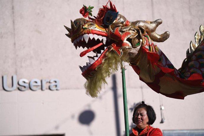 Archivo - Una mujer sujeta la cabeza de un dragón durante las celebraciones del Año Nuevo Chino en la plaza de Distrito de Usera.