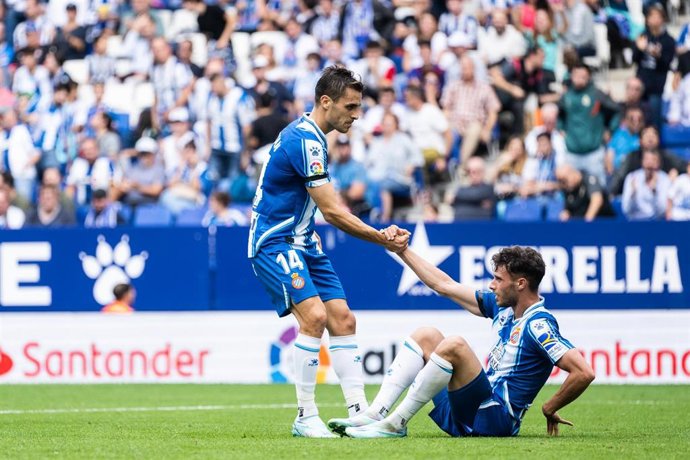 Archivo - Brian Olivan ayuda a levantarse a Javi Puado en un partido del Espanyol