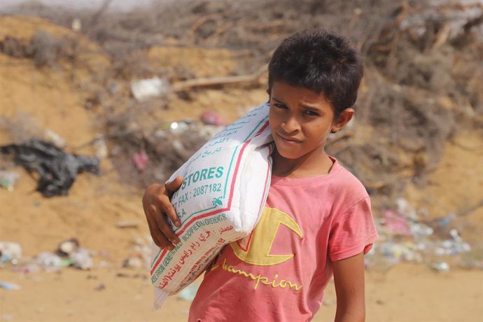 Archivo - Un menor carga con un saco de ayuda humanitaria en Yemen