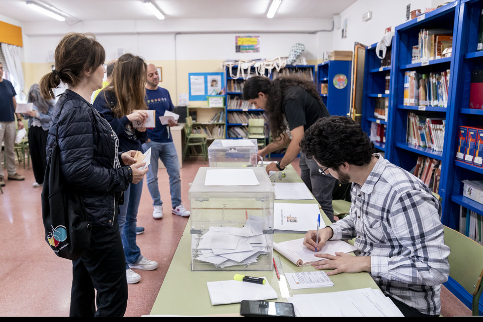 Varias personas se acercan a la mesa para votar en un colegio electoral, a 28 de mayo de 2023, en Madrid (España).  