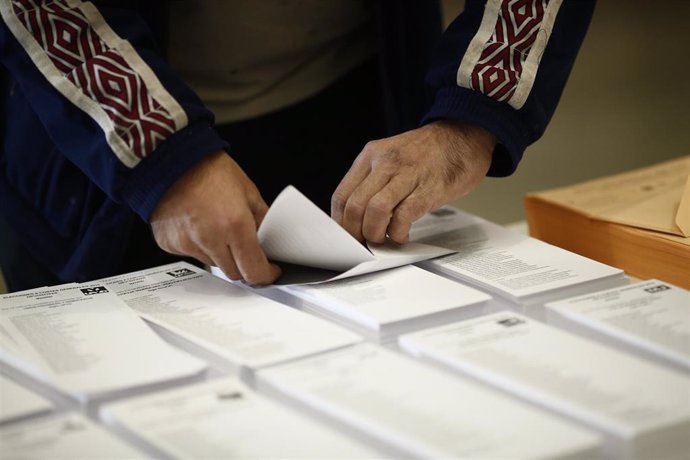 Archivo - Una persona introduce su voto en un sobre en un colegio electoral.